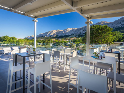 Modern outdoor terrace at Valamar Camping Baška, overlooking mountains in Primorje-Gorski Kotar, Croatia.