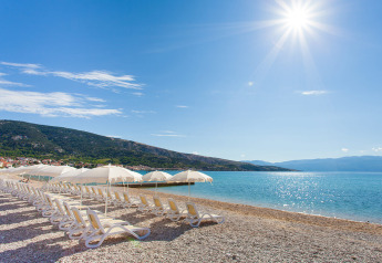 Spiaggia soleggiata con lettini e ombrelloni, Vela Bay Home al Valamar Camping Baška, Croazia.