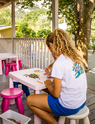 Kinder basteln und spielen an Tischen im Freien im Valamar Camping Baška, Primorje-Gorski Kotar, Kroatien.