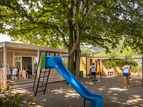 Speeltuin met glijbaan en schommels in de schaduw bij Valamar Camping Baška, Kroatië.