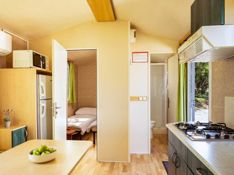 Interieur van chalet Brioni Home Seaside met slaapkamer, keuken en tafel op Camping Brioni in Kroatië.