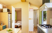 Interior of Brioni Home Seaside chalet showing cozy bedroom, kitchen area, and table at Camping Brioni, Croatia.