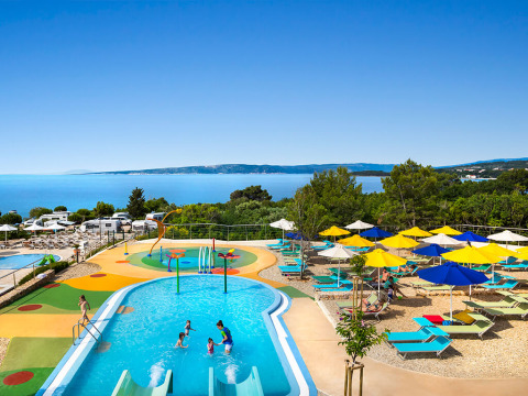 Zona infantil con piscina, sombrillas de colores y vistas al mar en Valamar Camping Krk, Croacia.