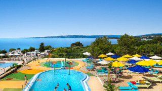 Kinderzwembad, kleurrijke parasols en zeezicht bij Valamar Camping Krk vakantiepark in Kroatië.