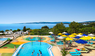 Kinderzwembad, kleurrijke parasols en zeezicht bij Valamar Camping Krk vakantiepark in Kroatië.