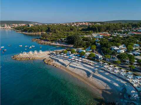 Luftfoto af kysten nær Krk i Primorje-Gorski Kotar, Kroatien, med stenstrand og klare, blå vand.