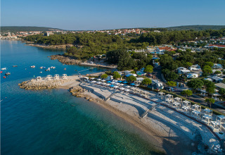 Vista aérea de la costa cerca de Krk en Primorje-Gorski Kotar, Croacia, con playa de guijarros y mar claro.