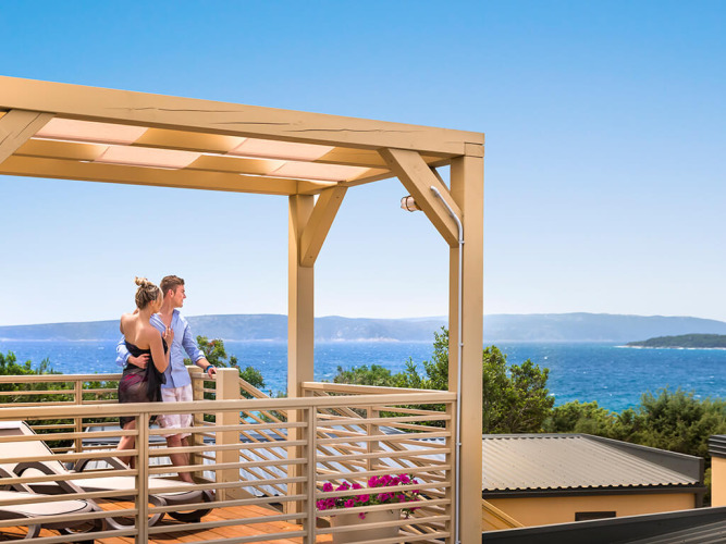 Pareja disfrutando vistas al mar desde la terraza Bella Vista Home Garden bajo la pérgola en día soleado.