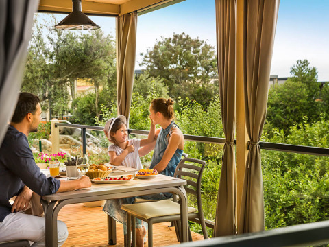 Familia disfruta del desayuno en la terraza cubierta de Bella Vista Home en Valamar Camping Krk, Croacia.
