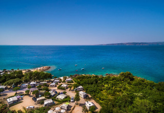 Campingvogne ved den smukke kyst nær Krk, omgivet af grønt og med udsigt over det krystalklare hav i Kroatien.