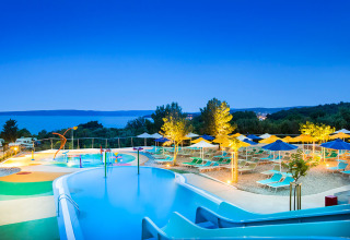 Verlicht zwembad en ligbedden bij Valamar Camping Krk in Primorje-Gorski Kotar, Kroatië bij zonsondergang.