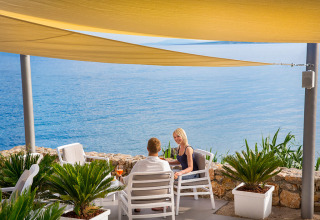 Pareja relajándose bajo toldos con vista al mar en Valamar Camping Krk, Primorje-Gorski Kotar, Croacia.
