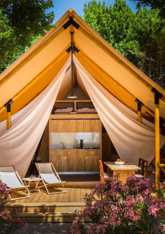 Luxe glampingtent met houten terras, ligstoelen en bloemenpracht bij Valamar Camping Krk in Kroatië.