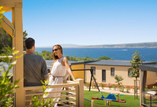 Pareja relajándose en la terraza Bella Vista Home Garden en Valamar Camping Krk con vista al mar en Croacia.
