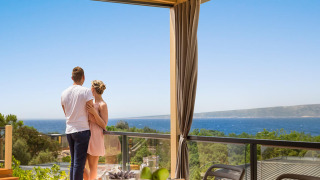 Stel geniet van het uitzicht op zee vanaf Bella Vista Home Spectacular view lodge met ontbijttafel buiten.