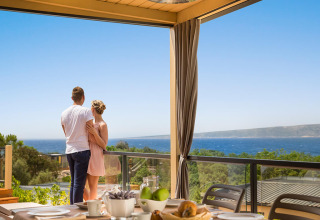 Paar genießt den Meerblick vom Bella Vista Home Spectacular view Lodge mit gedecktem Frühstückstisch.