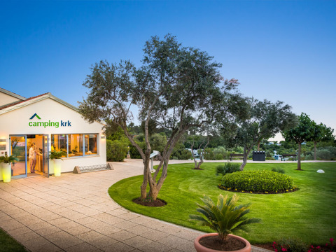 Entrance to Valamar Camping Krk, featuring a manicured garden and trees in Primorje-Gorski Kotar, Croatia.
