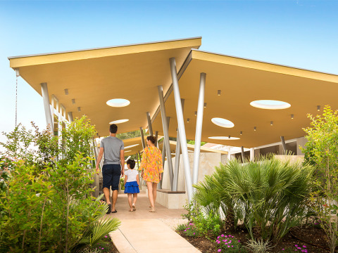 Een familie wandelt langs een pad omgeven door planten bij moderne gebouwen op Valamar Camping Krk, Kroatië.