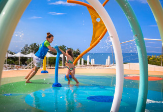 Children playing in a colorful splash park at Valamar Camping Krk holiday park with sea view in Croatia.