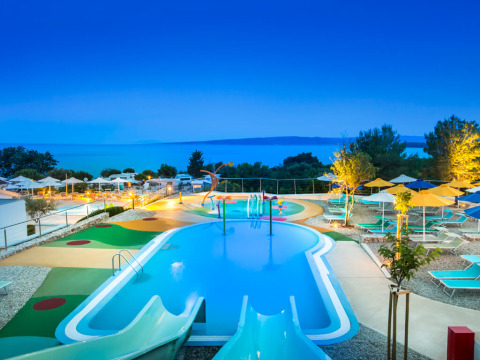 Piscina per bambini con scivoli e lettini a Valamar Camping Krk, Croazia, al tramonto vicino al mare.