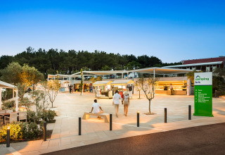 Avondfoto van Valamar Camping Krk in Kroatië met bezoekers, kraampjes en bomen op het plein.
