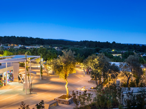 Evening lights illuminate Valamar Camping Krk holiday park in Primorje-Gorski Kotar County, Croatia, with trees.