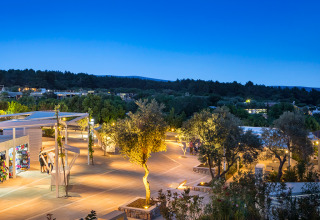 Luces nocturnas iluminan el parque Valamar Camping Krk en Primorje-Gorski Kotar, Croacia, rodeado de árboles.