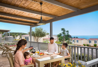 Famiglia fa colazione sulla terrazza del lodge Krk Home con vista mare e case vacanza sullo sfondo.