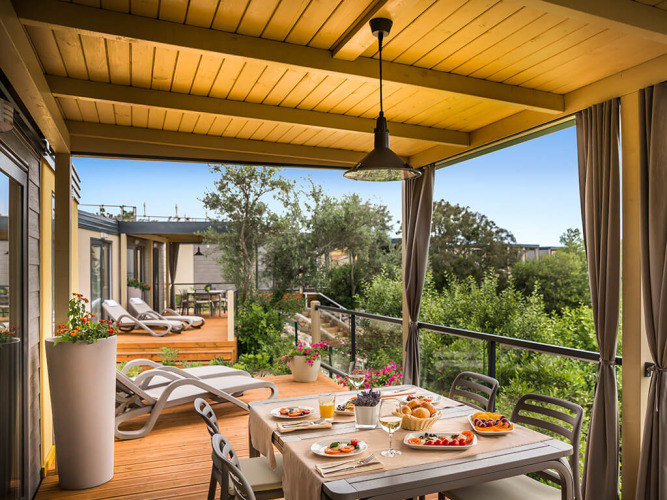 Overdekt terras van Bella Vista Home bij Valamar Camping Krk in Kroatië, met ontbijttafel en zicht op groen.