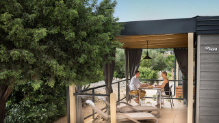 Coppia che gusta un pasto sulla terrazza del Bella Vista Chalet, immersa nel verde della natura.
