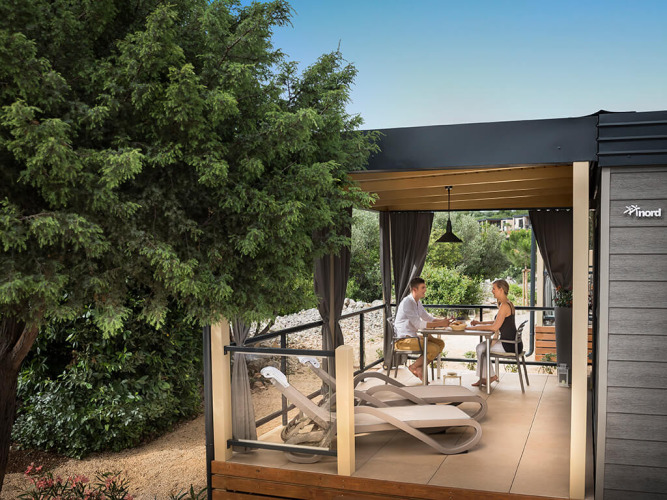 Par nyder et måltid på en afslappende terrasse på Bella Vista Chalet omringet af grønne træer og planter.