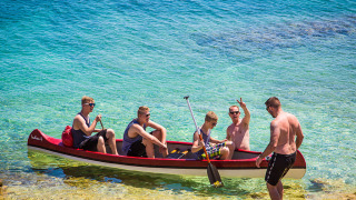 Fem mænd nyder en kano i det klare vand nær kysten i nærheden af Premantura, Istrien, Kroatien.