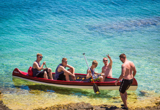 Vijf mannen genieten in een kano van het kristalheldere water nabij Premantura, Istrië, Kroatië.