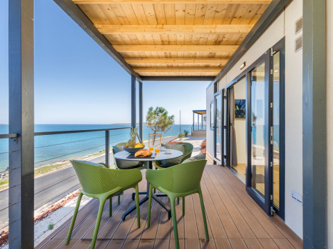 Terrazza vista mare con sedie verdi al Camping Arena Stupice, villaggio turistico in Istria, Croazia.