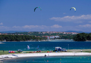 Beach and water sports at Camping Arena Stupice holiday park in Istria, Croatia, with town view nearby.