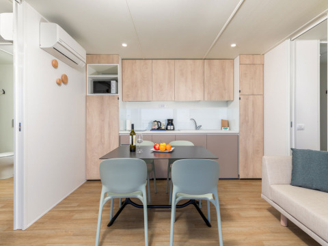 Cucina moderna e zona pranzo al Camping Home di Camping Arena Stupice, Croazia, con arredo in legno chiaro.