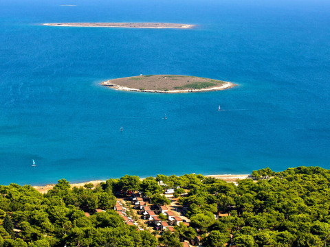 Vista aerea di isole e foresta costiera vicino a Premantura, Istria, Croazia, circondate da mare blu limpido.