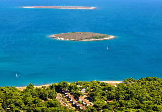 Aerial view of islands and shoreline forest near Premantura, Istria, Croatia, surrounded by clear blue sea.