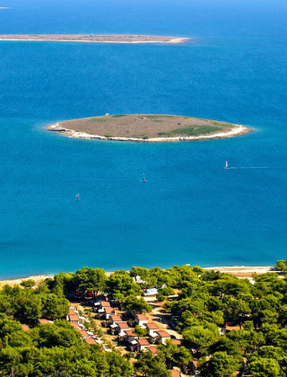 Luftfoto af øer og kystnær skov i nærheden af Premantura, Istrien, Kroatien, omgivet af klart blåt vand.