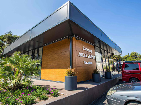 Moderne receptie van Camping Arena Stupice in Istrië, Kroatië, met planten en geparkeerde auto’s ervoor.