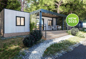 Lodge moderno Camping Home con terraza de madera rodeada de árboles, disponible como novedad en 2025.