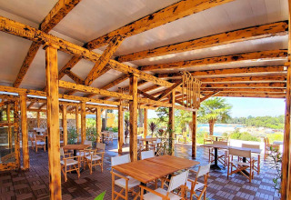 Buitenterras met houten tafels en stoelen bij Camping Porton Nature Hideouts in Istrië, Kroatië.