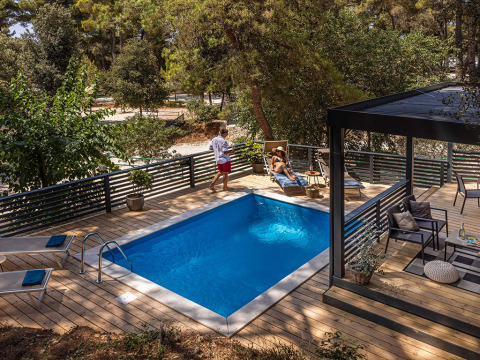 Terrazza in legno con piscina privata e lettini immersa nel verde al Porton Pool, Camping Porton Nature Hideouts, Croazia.