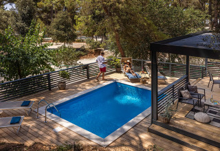 Wooden deck with private pool, sunbeds, and lush forest views at Porton Pool, Camping Porton Nature Hideouts, Croatia.