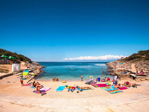Menschen entspannen an einem sonnigen Strand im Baia Holiday Poljana Ferienpark, Primorje-Gorski Kotar, Kroatien.