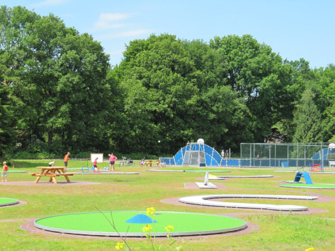 Foto van een vakantiepark met glamping en een midgetgolfbaan, gezinnen die van buitenactiviteiten genieten.
