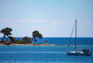 Velero en el mar azul en Baia Holiday Poljana con islas y árboles en Primorje-Gorski Kotar, Croacia.