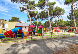 Aire de jeux colorée avec toboggans et balançoires à Baia Holiday Poljana, entourée de grands pins.