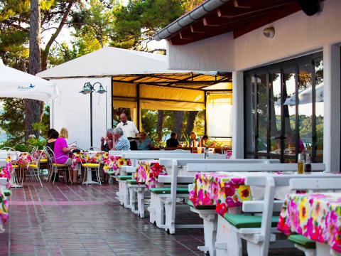 Außenrestaurant im Baia Holiday Poljana in Kroatien mit bunten Tischdecken und Gästen beim Essen.