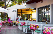 Restaurante al aire libre en Baia Holiday Poljana, Croacia, con manteles coloridos y comensales disfrutando.